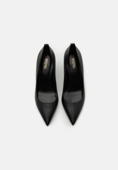 Escarpins en cuir noir avec un bout pointu, une texture lisse et un petit talon. Présentent un marquage visible sur la semelle intérieure.