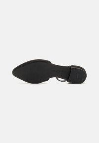 Sorte hæler med spiss tå-design, med en elegant materialefinish og en teksturert gummisåle med sklisikre detaljer.
