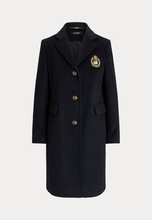 Παλτό σε μπλε ναυτικό χρώμα από μείγμα μαλλιού με γιακά με υποδοχή, χρυσά κουμπιά και λεπτομέρεια με έμβλημα. Διαθέτει δύο μπροστινές τσέπες και εφαρμοστό σχήμα.