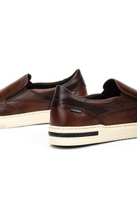 Bruine leren instapschoenen met een gladde textuur, contrasterende zwarte accenten op de zool en een stevige witte buitenzool.
