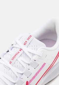 Baskets Nike Air Zoom Pegasus 38 blanches avec des lacets blancs, des détails de couture rouges et un texte rouge sur la languette.