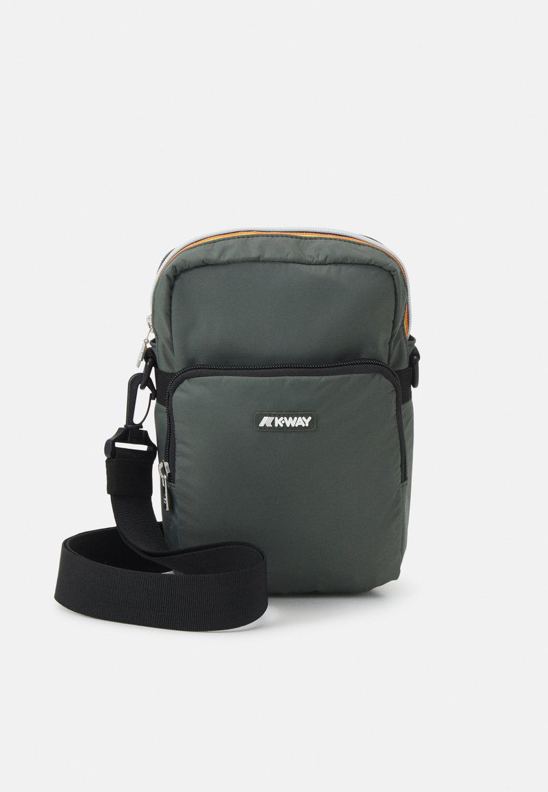 Borsa a tracolla imbottita verde con cerniera nera, hardware argentato, fodera arancione e tracolla regolabile. Sul fronte è presente un'etichetta con logo.