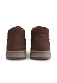 Botas de ante marrón con un acabado texturizado, altura hasta el tobillo, con una suela beige y elementos de cordones mínimos para un ajuste seguro.