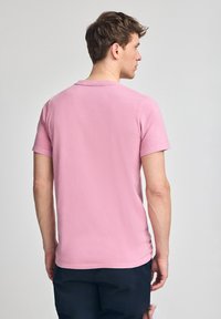 T-shirt rosa a maniche corte realizzato in morbido cotone. Presenta un colletto a girocollo e una vestibilità comoda, con una texture liscia e design semplice.