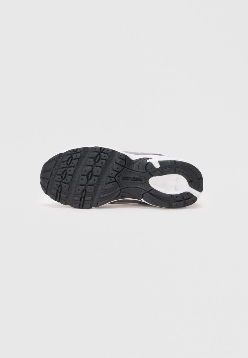 Semelle extérieure en caoutchouc noir avec des crampons profonds, intermédiaire en mousse blanche, et un dessus texturé présentant des tons de gris et un branding subtil.