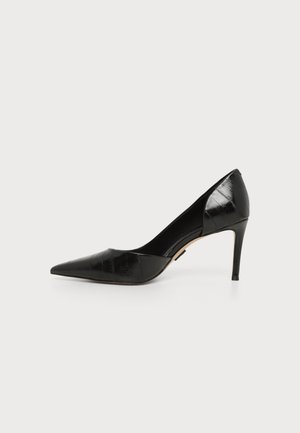 Chaussure à talon haut noire à bout pointu avec un talon aiguille fin et une finition en cuir texturé, montrée de profil sur fond blanc.