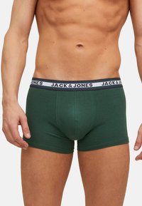 Groene katoenen boxershorts met een aansluitend ontwerp, voorzien van een gebrandmerkte elastische tailleband in donkerblauw en wit. Gladde textuur, lengte tot halverwege de dij.