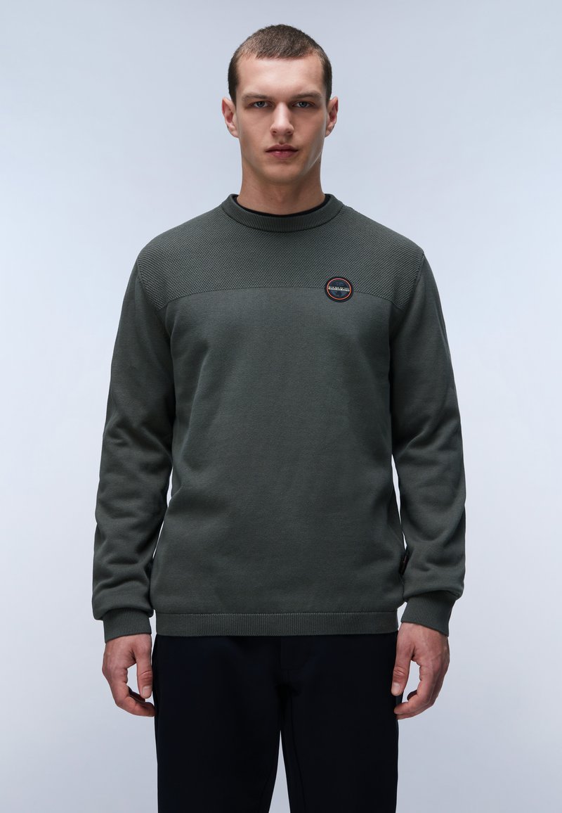 Felpa verde a maglia con sezione superiore testurizzata, colletto e polsini a costine, patch con logo sul petto e vestibilità rilassata. Materiale misto cotone.