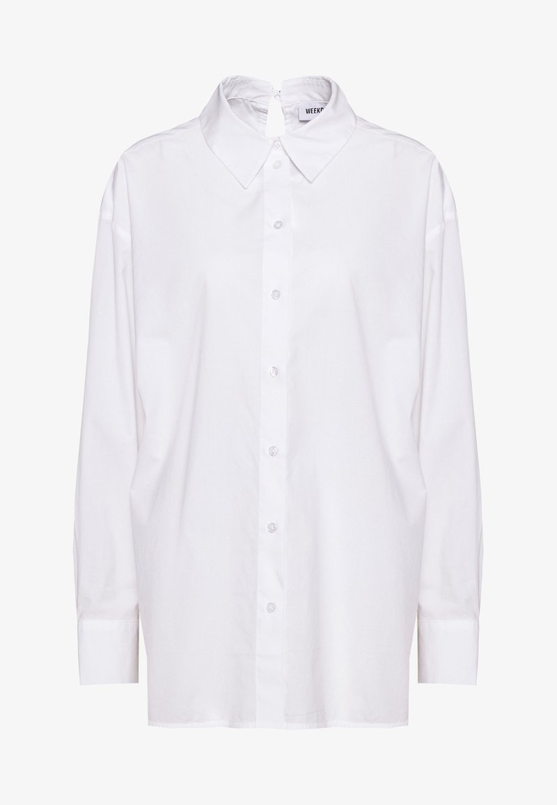 Chemise blanche à manches longues boutonnée avec col pointu et fermeture à œillet au niveau de l'encolure au dos.
