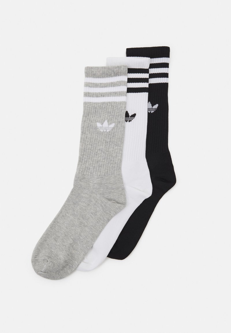 Tri para posadnih nogavic: sive z belimi črtami, bele s črnimi črtami in črne z belimi črtami. Vsaka ima logotip Adidas.