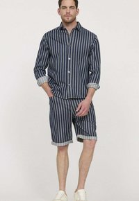 Ensemble de chemise et short à rayures marines, fabriqué en tissu léger. La chemise a un devant boutonné et des poignets repliés, le short présente des ourlets retournés.