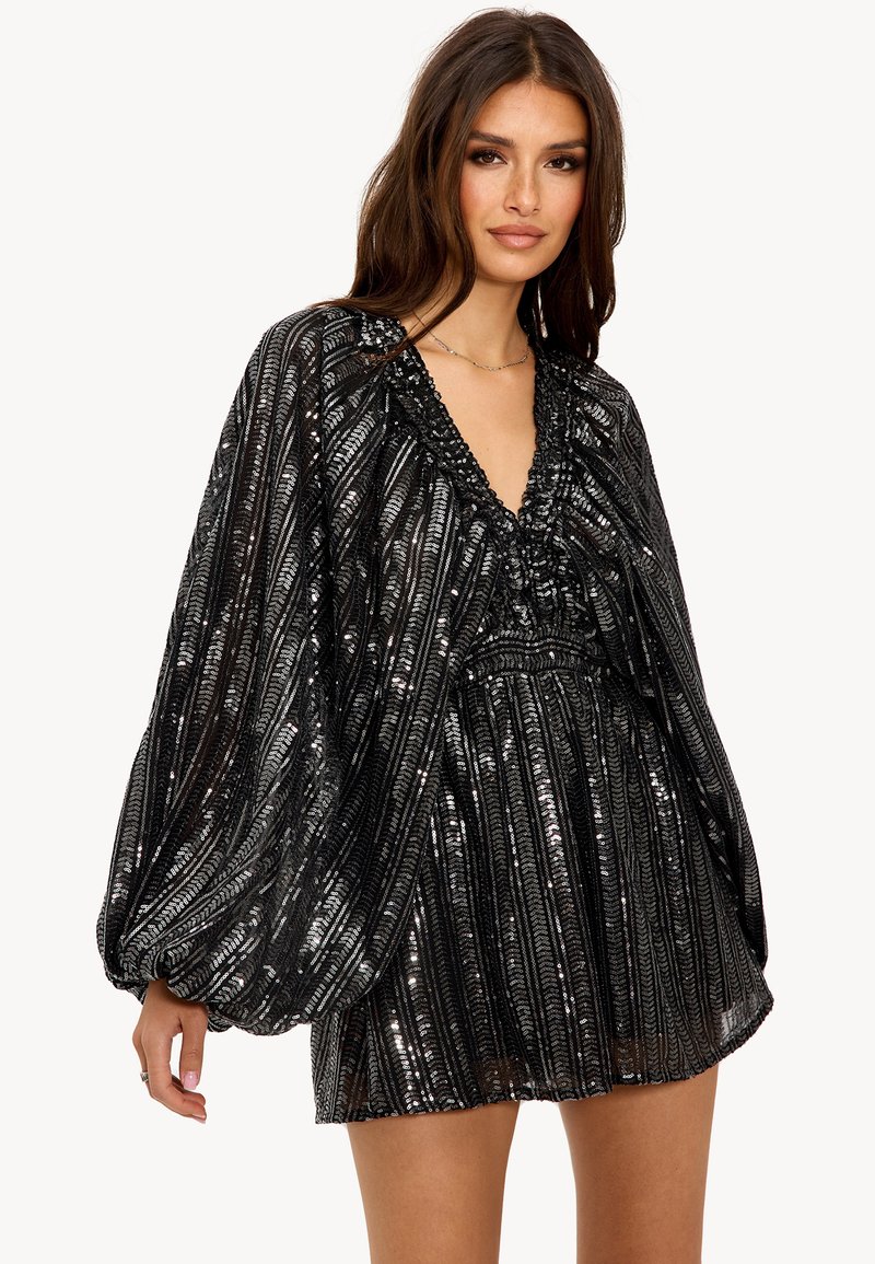 Robe noire avec un décolleté en V, ornée de sequins en rayures verticales. Elle possède des manches bouffantes et une taille cintrée avec des accents volantés.