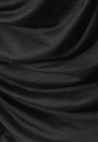 Tessuto nero con una texture morbida e liscia, caratterizzato da pieghe drappeggiate che creano profondità e interesse visivo, sottolineando la leggerezza del materiale.