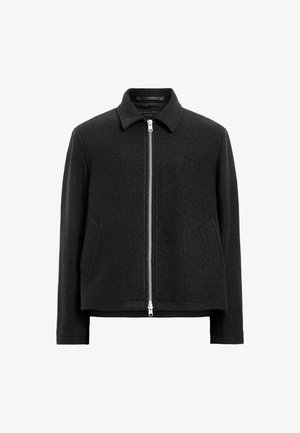 Chaqueta negra de mezcla de lana con cierre de cremallera en la parte delantera, cuello puntiagudo, dos bolsillos laterales y una silueta estructurada y ligeramente rectangular.