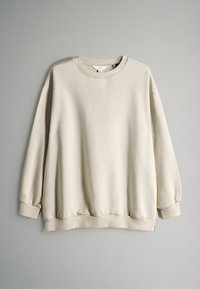 Béžová mikina s kulatým výstřihem, spadlými rameny a žebrovanými manžetami. Měkká látka s mírně texturovaným povrchem a elastickým spodním lemem.