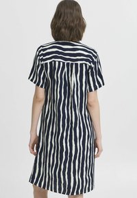 Rochie din in în dungi bleumarin și alb, cu mâneci scurte, croi până la genunchi, și un model cu dungi verticale, având un detaliu cu yoke în spate cu nasturi.