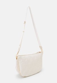 Pletená bílá kabelka přes rameno se zlatým kováním, nastavitelným popruhem a zipovým uzavřením. Na vnějším povrchu má diamantový vzor.