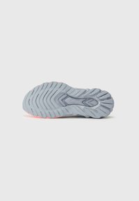Suola di scarpa sportiva grigia con un motivo di battistrada ondulato, caratterizzata da scanalature testurizzate e un accento rosa sul tallone che circonda il numero del modello.