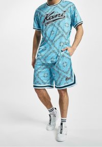 Sky blue matching shorts and t-shirt set, featuring a bandana pattern, black trim, and logo. Made from breathable fabric.