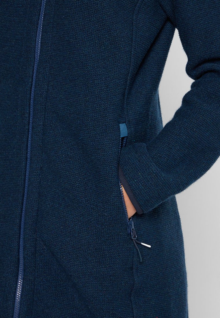 Cappotto lavorato a maglia blu navy con finitura testurizzata, dotato di una cerniera centrale e tasche laterali. I polsini sono rifiniti in una tonalità più scura.