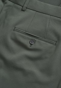 Pantalones en verde oscuro hechos de una tela texturada, con un bolsillo trasero y un botón oscuro. Corte recto con pliegues planchados.