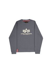 Sweat-shirt gris avec un logo crème comprenant un triangle abstrait et des rayures. Poignets et ourlet côtelés, avec une étiquette rouge en bas à gauche.