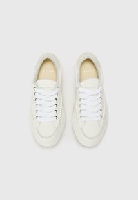 Baskets en cuir blanc avec un col en daim gris texturé, un devant à lacets et des lacets blancs. Présente un logo discret sur la semelle intérieure.