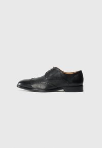 Chaussure de costume pour homme en cuir noir avec des d�étails en brogue et des lacets, présentée en profil latéral droit sur un fond blanc.