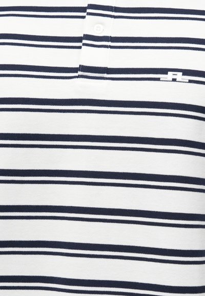 Άσπρο πόλο μπλουζάκι με οριζόντιες ναυτικό μπλε ρίγες και ένα μικρό λευκό κεντητό λογότυπο κοντά στην ραφή με τα κουμπιά στο στήθος.