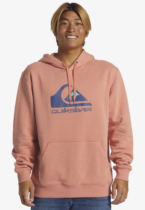 Pink hoodie with a large blue Quiksilver logo. Features a drawstring hood, front pocket, and ribbed cuffs. Smooth texture.