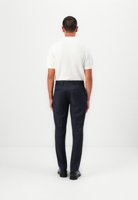 White short-sleeve pullover and dark navy tailored trousers, featuring a smooth texture and minimalistic design, with black dress shoes.