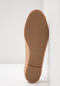 Scarpa beige chiaro con tomaia in pelle liscia e suola in gomma testurizzata, con logo del marchio in rilievo sulla suola e design senza cuciture.