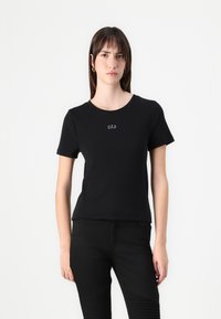 T-shirt en coton noir à manches courtes, avec un col rond et un petit logo "GAP" blanc à l'avant. Design simple et ajusté.