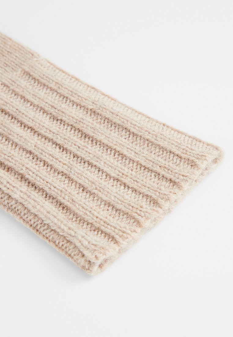 Beige gestrickter Schal mit gerippter Struktur, der abwechselnd hellere und dunklere Töne aufweist. Weiches, warmes Material, rechteckige Form und saubere Kanten.