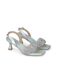 Tacchi slingback metallici argento con design a punta quadrata. Accento decorativo intrecciato con strass. Tacco basso, arrotondato con base testurizzata.