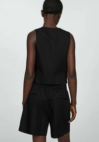 Czarny krótki top o gładkiej teksturze i okrągłym dekolcie, w zestawie z czarnymi szortami z elastycznym pasem i tylnymi kieszeniami.