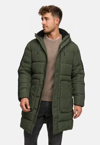 Gevoerde groene parka met een capuchon, textuurstof, voorzakken en zwarte zijkanten, met een rits- en drukknoopsluiting.
