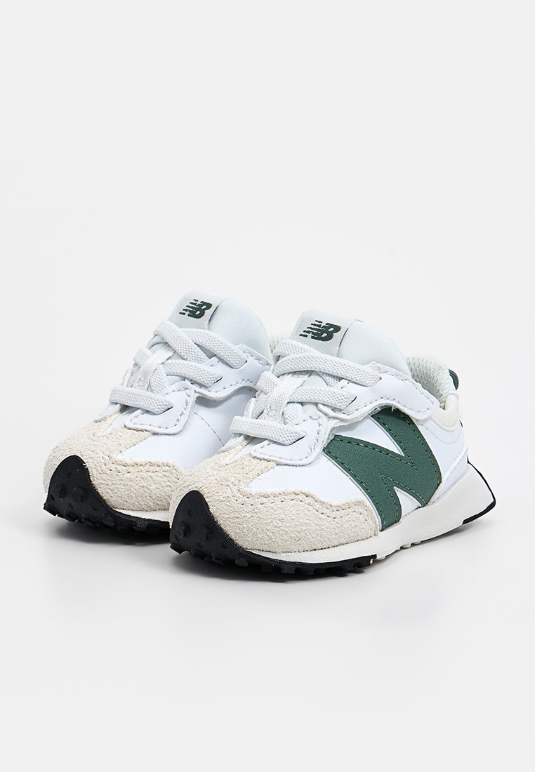 Baskets blanches avec un logo "N" vert, un bout beige texturé et des accents gris. Elles sont équipées de lacets ronds et d'une semelle en caoutchouc noire.