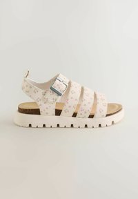 Sandale blanche avec motif floral rose, boucle argentée réglable, semelle intérieure en liège rembourrée et semelle épaisse blanche à crampons.