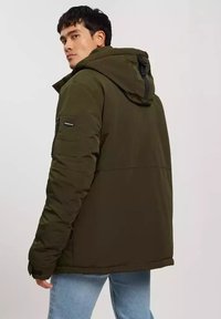 Ciemnozielona kurtka puchowa z kapturem, z zamkiem błyskawicznym z przodu, elastycznymi mankietami i kieszenią naszywaną na rękawie. Gładka tekstura.