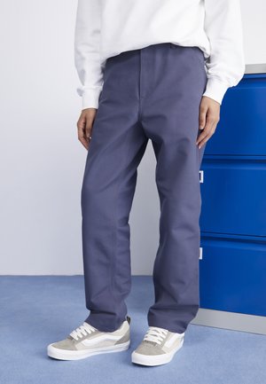 Pantalones oscuros azules, rectos y ligeros, fabricados con un tejido duradero, que presentan una textura suave y detalles de costura limpios, combinados con zapatillas grises.
