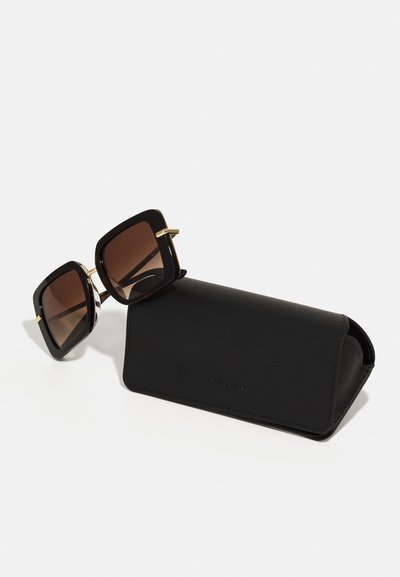 Zwarte vierkante zonnebril met gradiënt bruine lenzen, gouden accenten en een bijpassende zwarte beschermhoes. Gladde textuur, minimalistisch design.