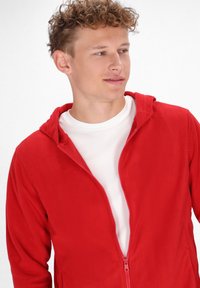 Giacca in fleece rosso con zip e cappuccio, caratterizzata da una texture morbida e uno strato interno bianco. Include una zip frontale, progettata per l'abbigliamento casual.