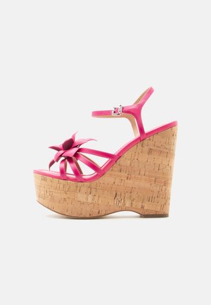 Sandalia de cuña con tacón alto en color rosa, plataforma de corcho, tira en el tobillo y detalle decorativo de flor en las tiras delanteras.