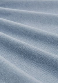 Lichtblauwe katoen stof met een gladde textuur, met fijne diagonale lijnen en zachte plooien, die flexibiliteit en drapeert aangeven.