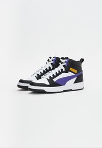 Mustvalged mustad ja valged titeketsi, millel on lillad aktsendid, tekstureeritud nahk, perforeritud varvas ja PUMA logo oranžis värvis.