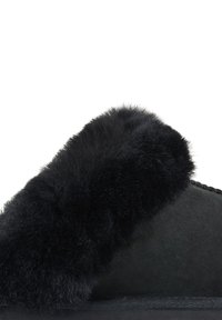 Black suede slipper with a plush, black fur trim. Soft texture, rounded shape, and decorative stitching along the upper. No visible hardware.