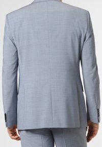 Jasnoniebieska marynarka z tkaniny o fakturze, z pojedynczym rozcięciem z tyłu i rękawami zapinanymi na guziki. Prosty, nowoczesny fason.