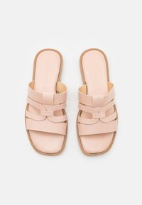 Pink slide sandals featuring wide straps and a flat sole, crafted from smooth material with a subtle sheen and reinforced edges.
