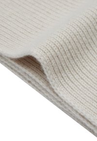 Tessuto di lana lavorato a maglia di colore bianco sporco con una trama a coste, che mostra una tessitura morbida e flessibile. I bordi sono rifiniti in modo pulito.